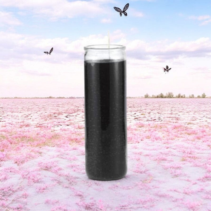 Black Protection Ritual Candle sits outdoors with soft focus pink flower petals, flying butterflies, and blue sky in the background.