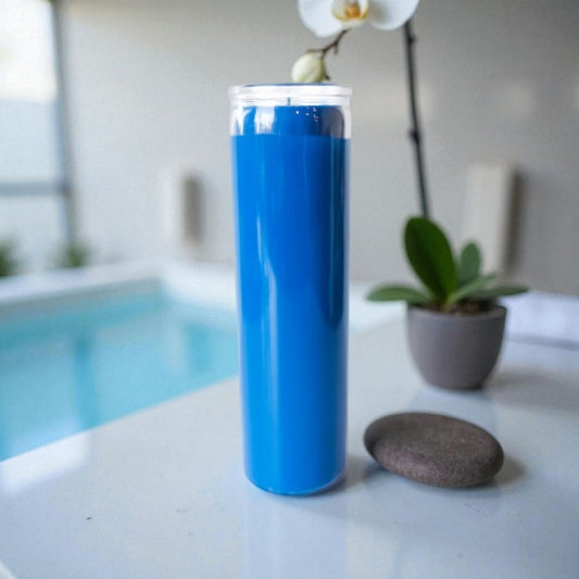 Unscented 7-day Light Blue candle on white surface with a stone and orchid, creating a calm, spa-like atmosphere.