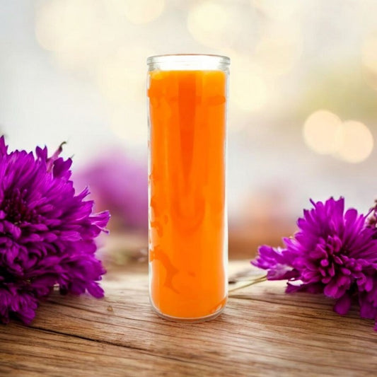 Tall orange 7-day ritual candle on a wooden surface, surrounded by purple flowers. Represents confidence, success, and motivation. 